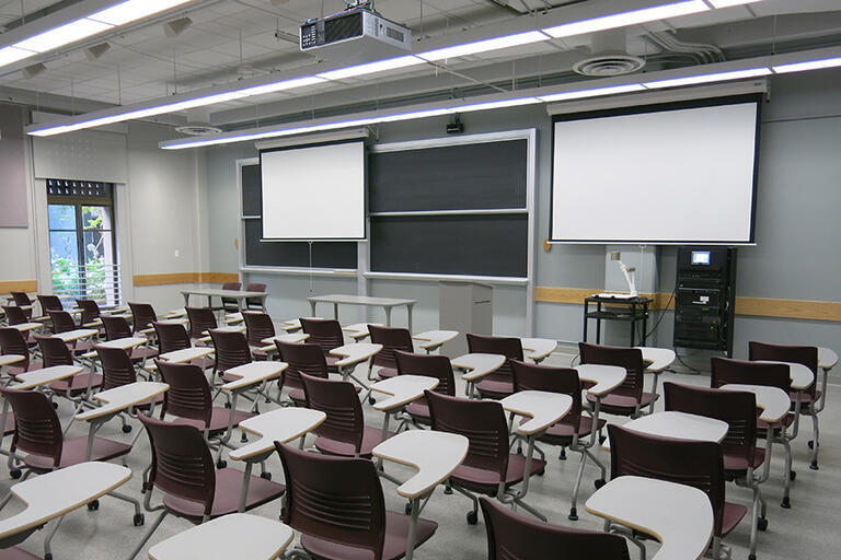 Etcheverry 3108 has 75 movable desks with a moveable speaker podium facing the class. The AV rack/blackbox is in the front of the classroom near the four-panel blackboard near the moveable Document Camera. There are two projector screens, one of which tha